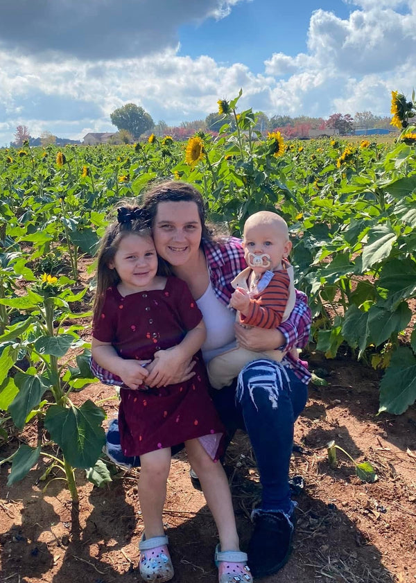 Woman with two children in a sunflower field on a sunny day